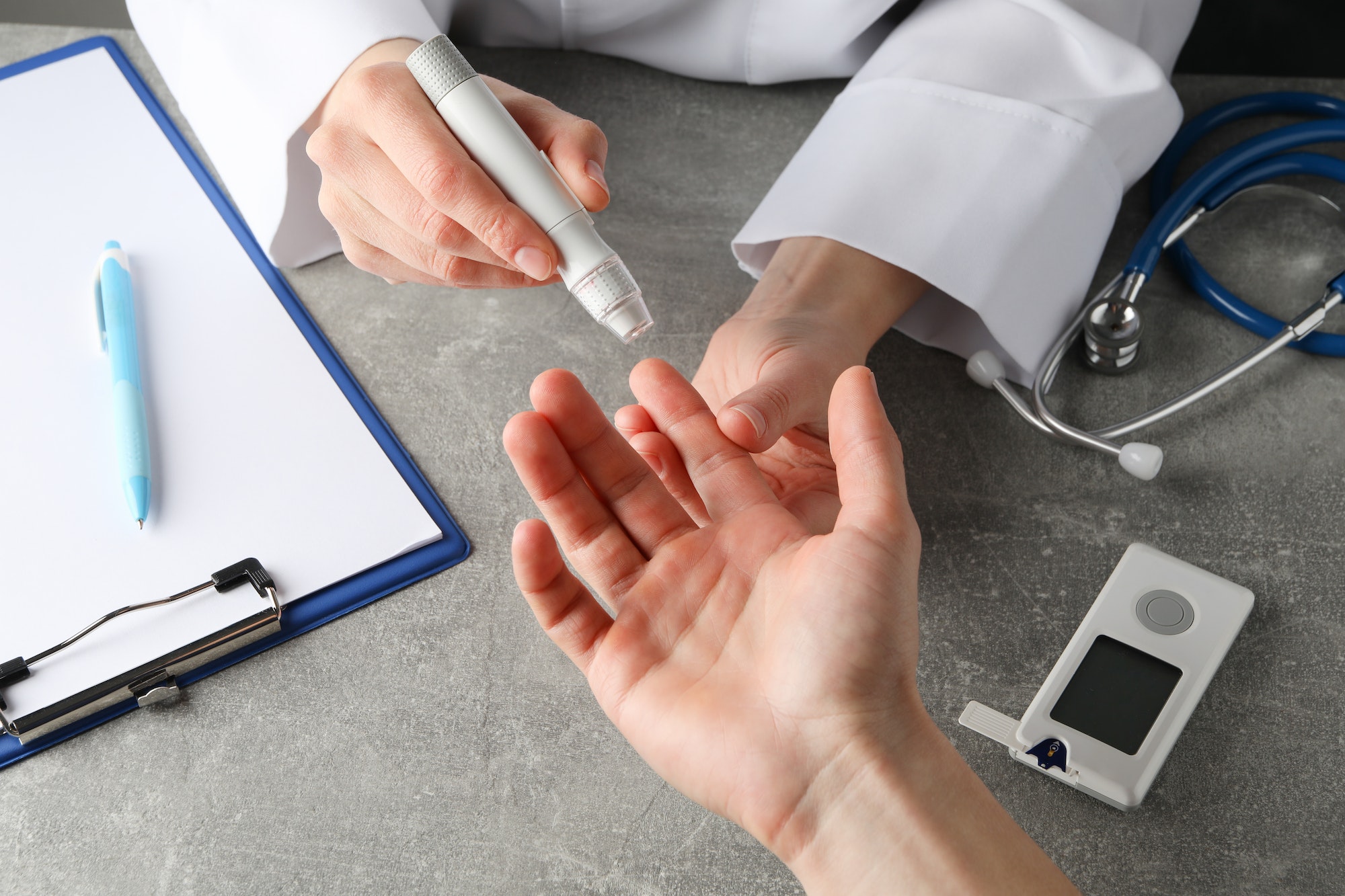Doctor checking blood sugar level in patient diabetes on gray table