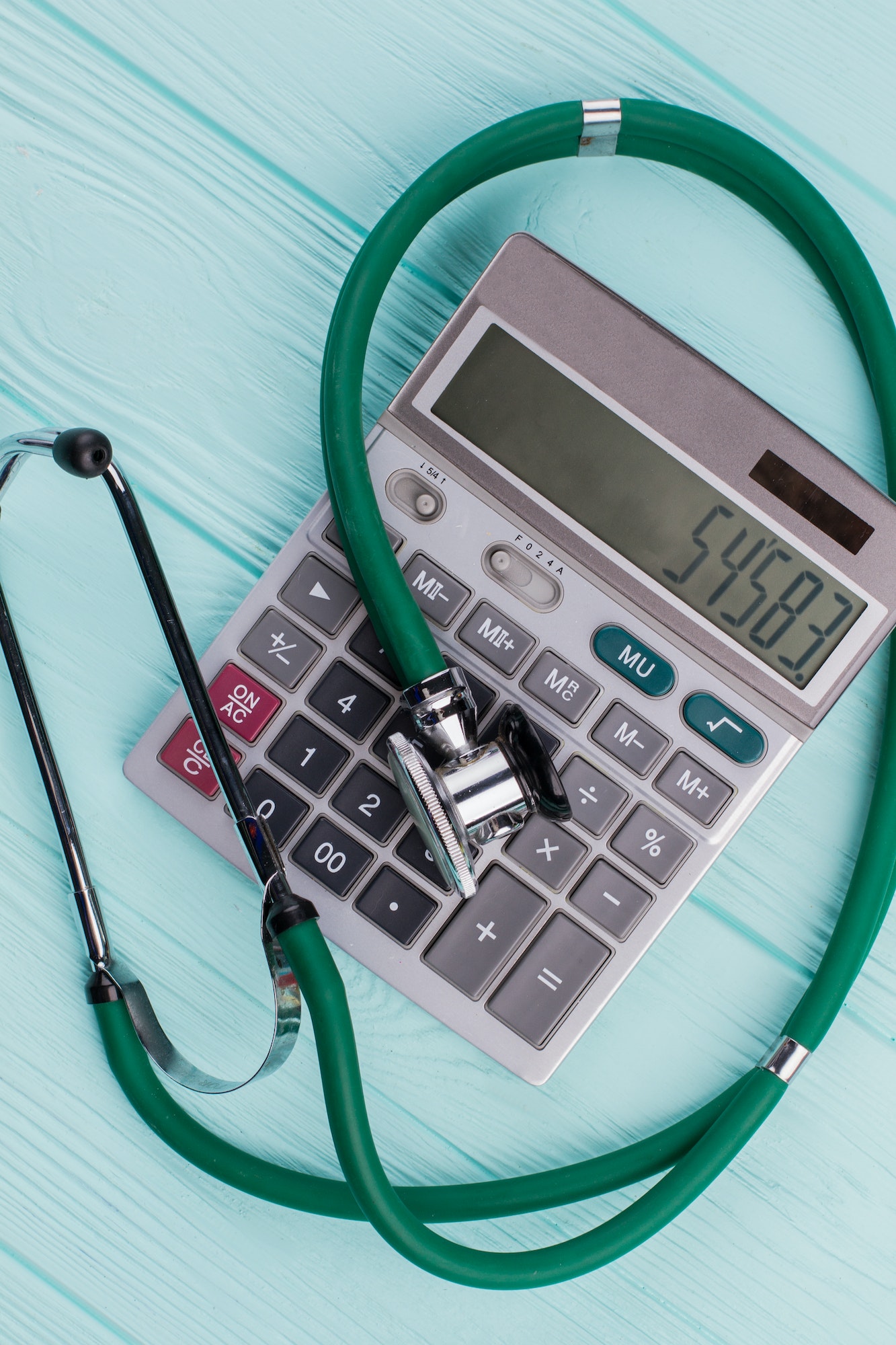 Green stethoscope on calculator.